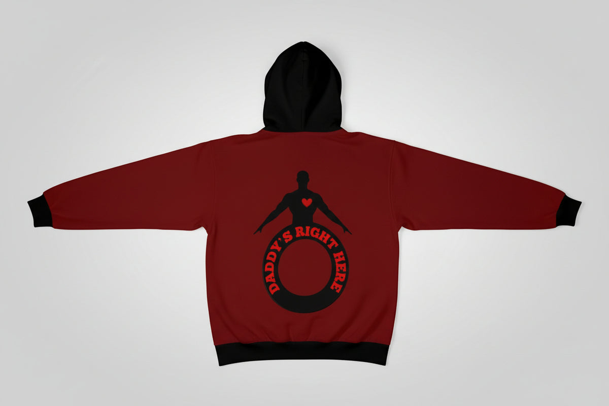 A man viewed from the back wearing a dark red hoodie with a black hood and a large back graphic featuring a black silhouette, a small red heart, and the words 'DADDY'S RIGHT HERE' in red inside a black ring.