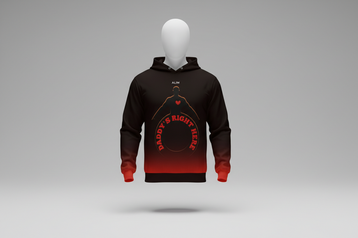 A man viewed from behind wearing a black hoodie with a red and orange graphic on the back that reads 'Daddy's Right Here' with a silhouette and heart. He is standing on a city street next to a newspaper stand.